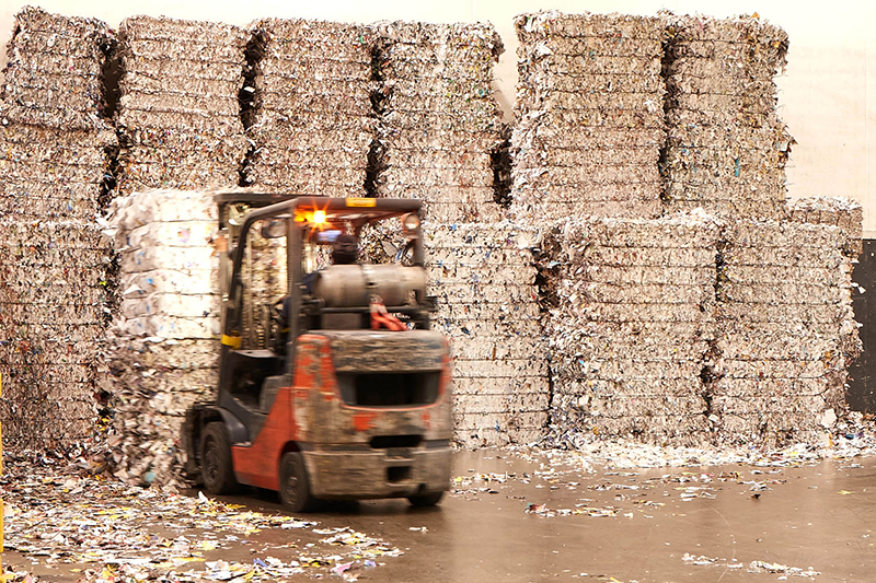 Forklift driver moving pallets of shredded material in Quad’s Sussex recycling center Forklift placing bundle of shredded paper into larger stack in Quad's Sussex recycling center