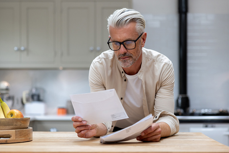 Middle-aged man looking through direct mail Middle-aged man looking through direct mail