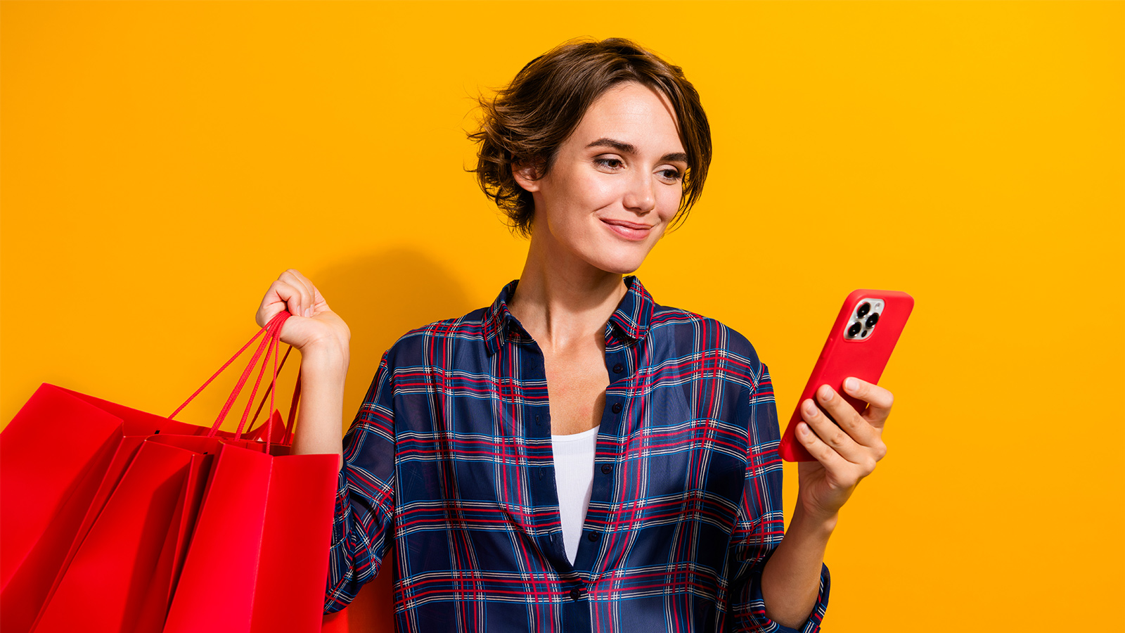 Mujer sosteniendo bolsas de compras y mirando su teléfono