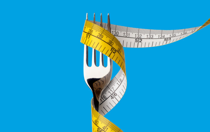 Tenedor con cinta métrica envuelta alrededor con fondo azul