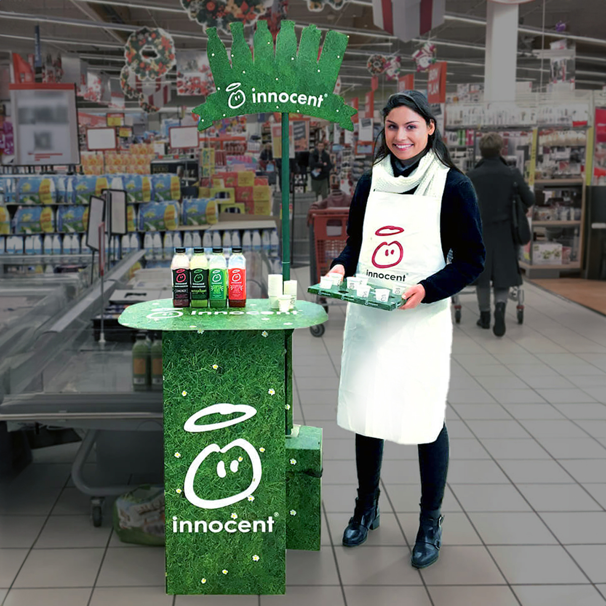Employee standing next to an in-store display for free product samples Employee standing next to an in-store display for free product samples